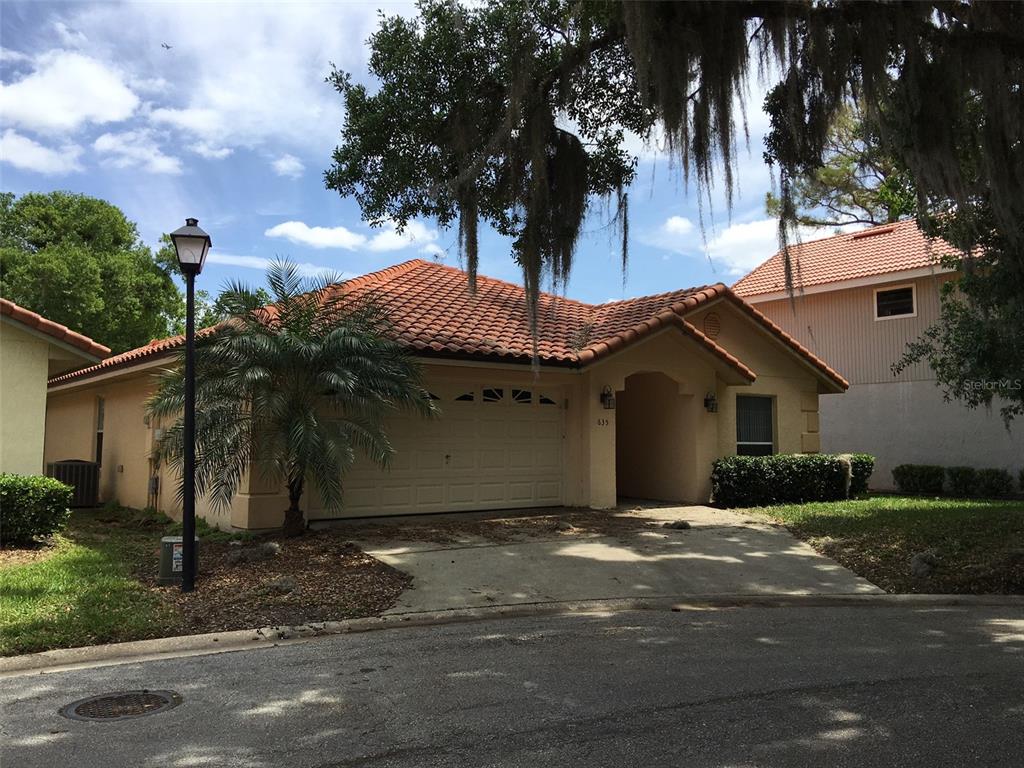 A single-story house with a terracotta tile roof, a garage, and a palm tree — 635 NIGHTHAWK CIRCLE, WINTER SPRINGS, FL
