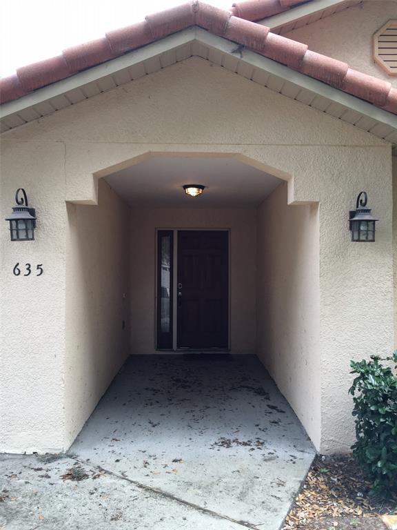 A covered entryway with a dark wood front door, two wall sconces, and house numbers — 635 NIGHTHAWK CIRCLE, WINTER SPRINGS, FL