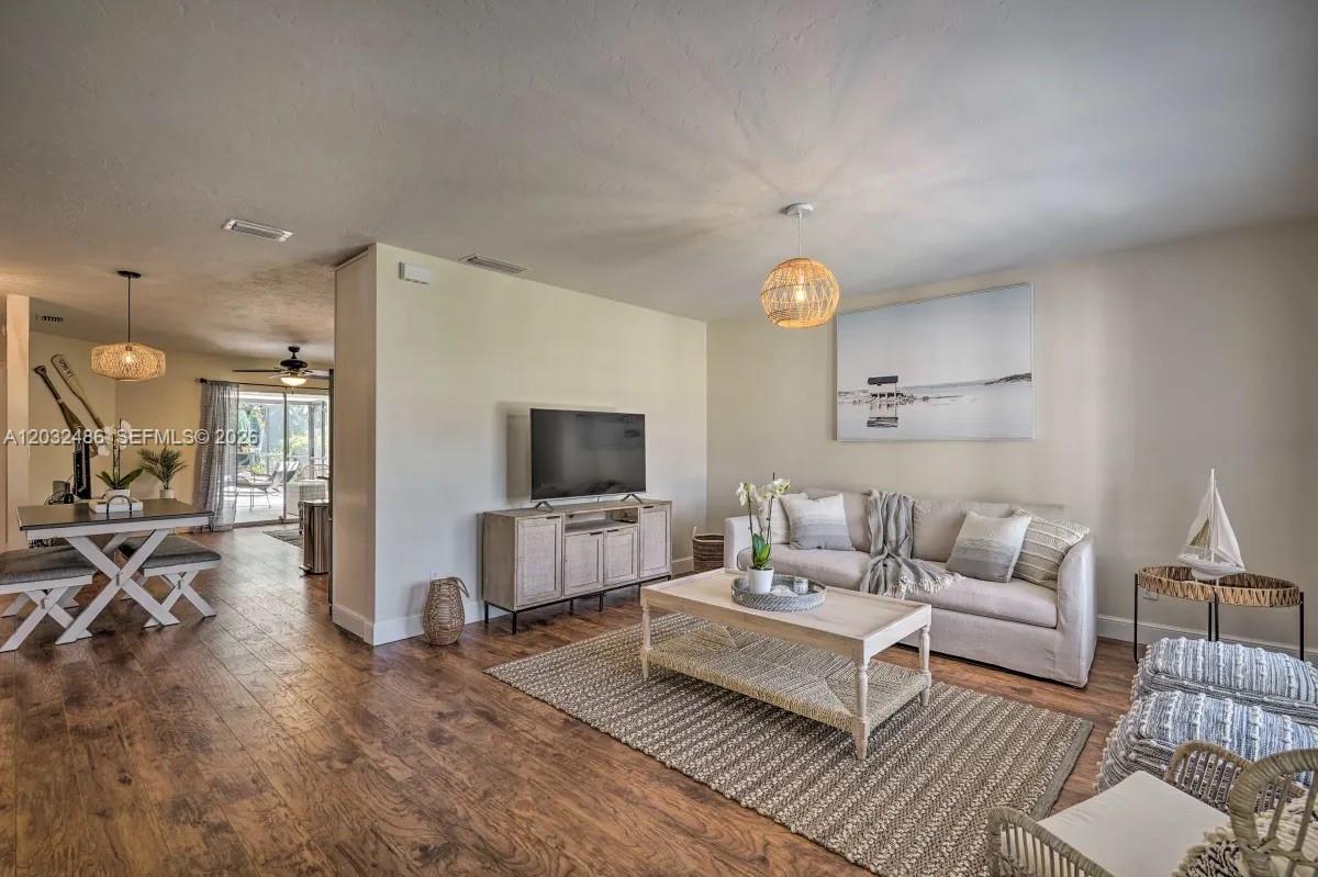 A living room features light wood floors, a beige sofa, and a television on a console — 558 102nd Ave # 0, Naples FL 34108, NAPLES, FL