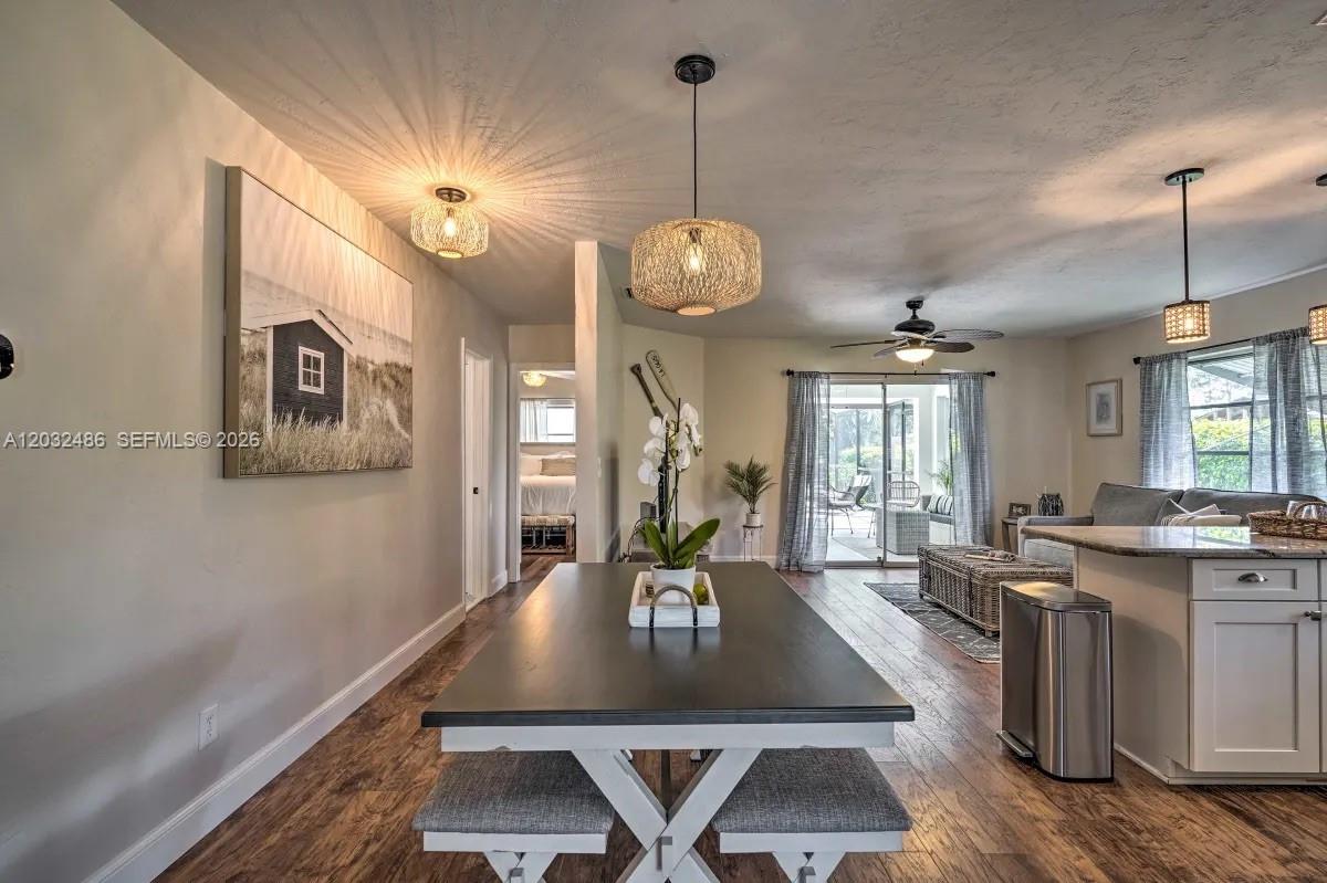 A dining area with a dark table and benches leads to a living room with sliding doors — 558 102nd Ave # 0, Naples FL 34108, NAPLES, FL