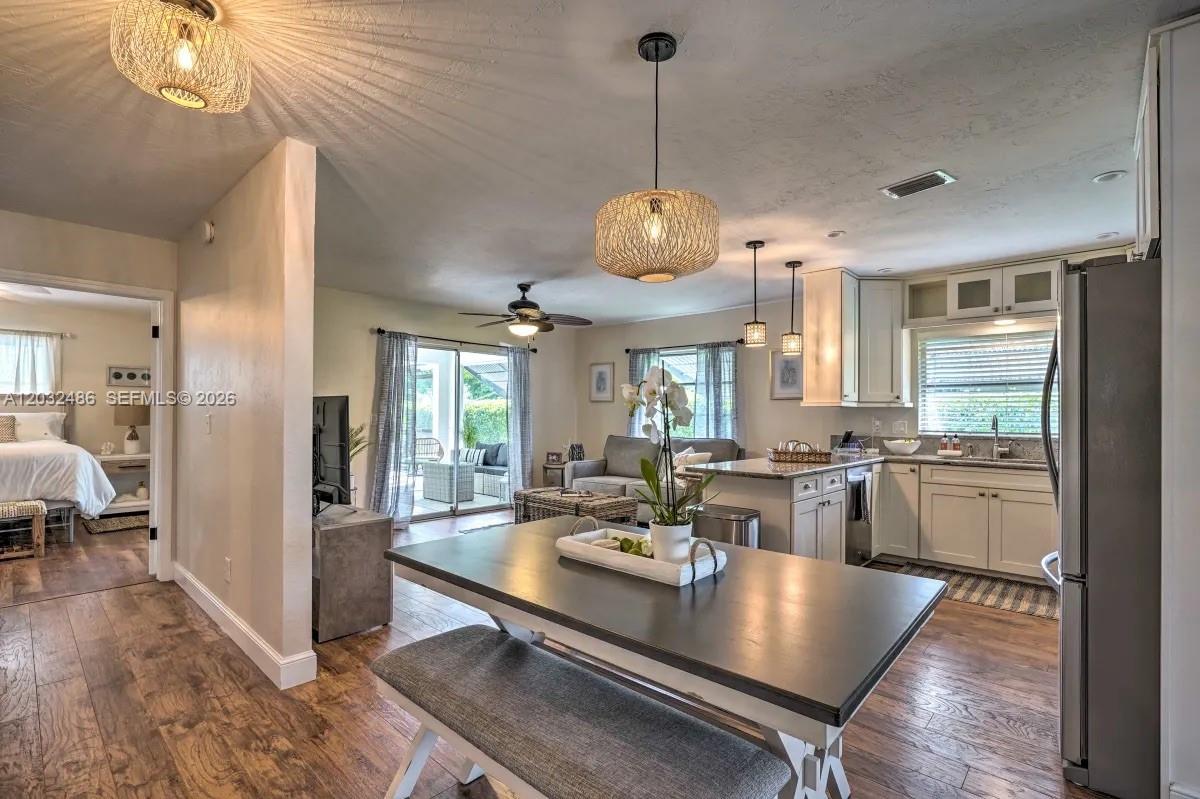 An open-concept kitchen and dining area features wood flooring, pendant lighting, and a center island — 558 102nd Ave # 0, Naples FL 34108, NAPLES, FL