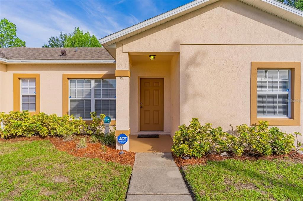 The exterior of a beige house features a brown front door and a concrete walkway — 7 TAMIAMI WAY, KISSIMMEE, FL