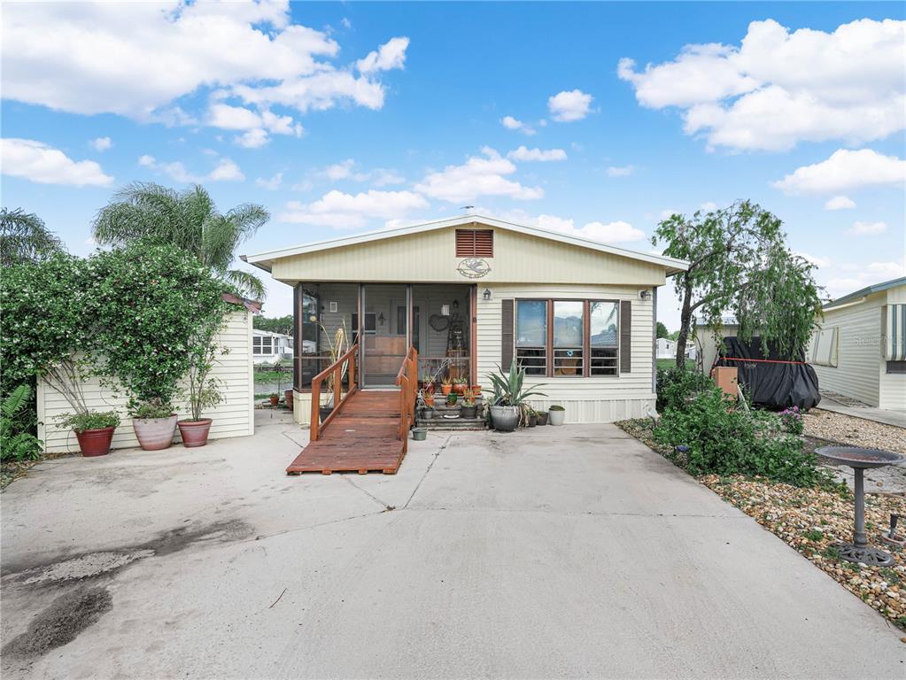 A single-story mobile home with a wooden ramp leading to a screened-in front porch — 29 BEAVERKILL DRIVE, LAKE WALES, FL