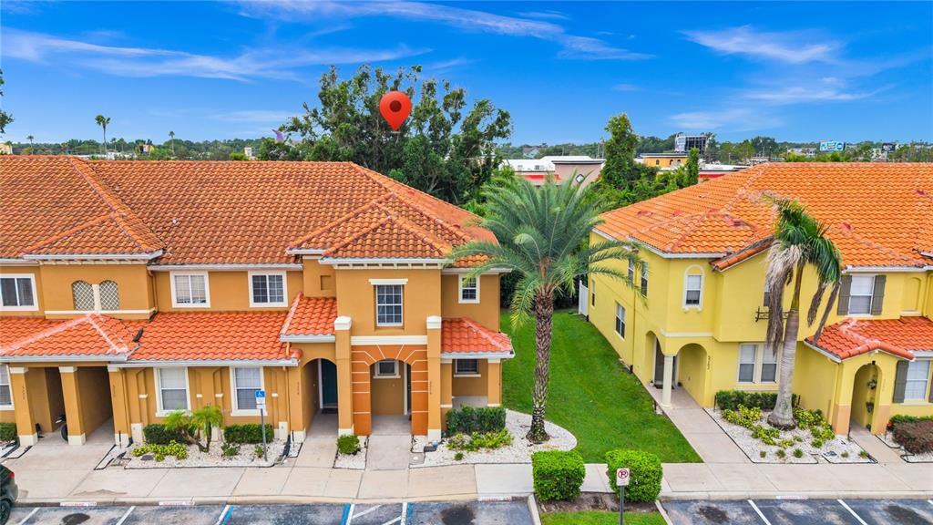 An exterior view of two adjacent multi-story townhomes with orange tile roofs and palm trees — 5266 PARADISE CAY CIRCLE, KISSIMMEE, FL