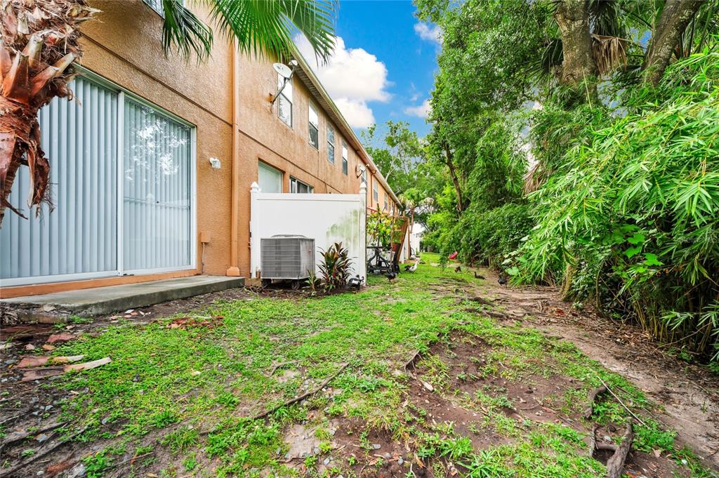 A view of a backyard with a concrete patio, an air conditioning unit, and landscaping — 5266 PARADISE CAY CIRCLE, KISSIMMEE, FL
