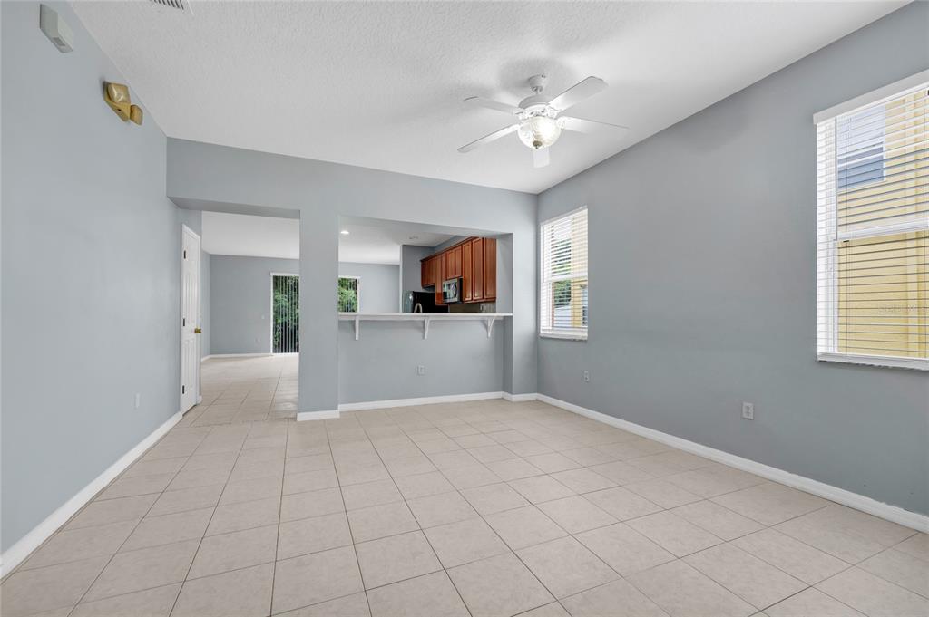 A living room with light gray walls, tile flooring, a ceiling fan, and a kitchen pass-through — 5266 PARADISE CAY CIRCLE, KISSIMMEE, FL