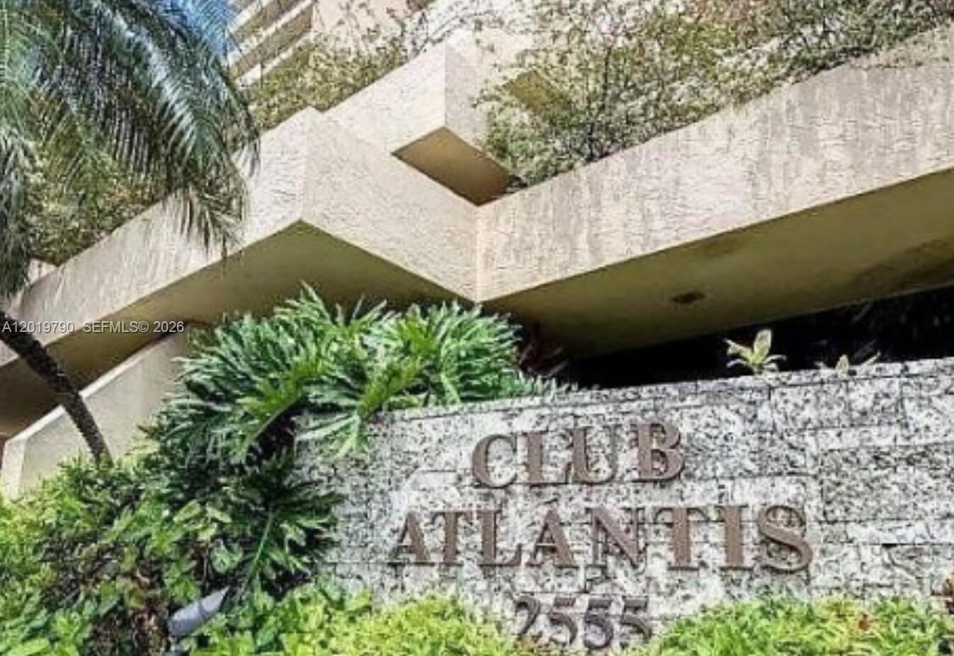 The exterior of a multi-story building features a stone sign reading Club Atlantis 2555 — 2555 Collins Ave # 1003, Miami Beach FL 33140, MIAMI BEACH, FL