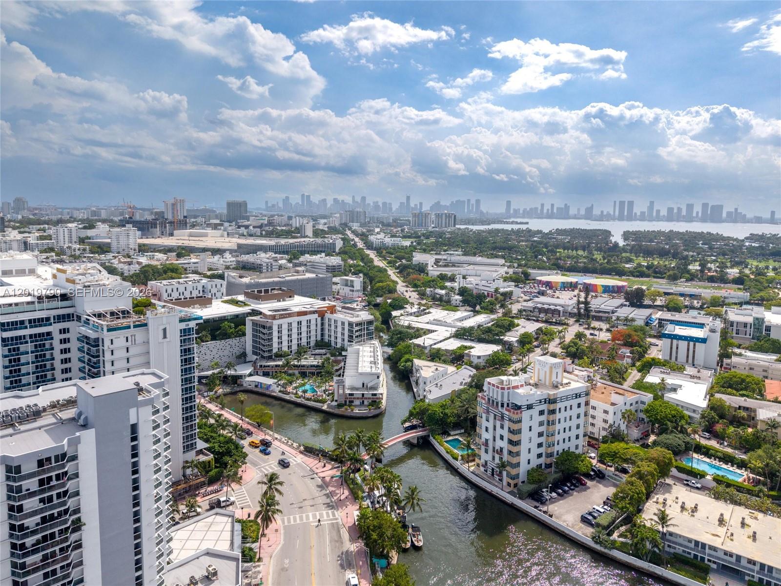 An aerial view shows a canal winding through a city with high-rise buildings and palm trees — 2555 Collins Ave # 1003, Miami Beach FL 33140, MIAMI BEACH, FL