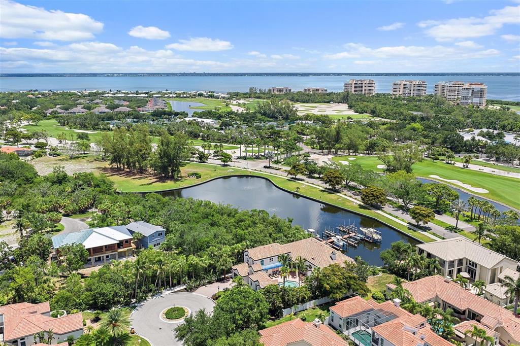 An aerial view shows waterfront homes, a golf course, and a large bay in Florida — 617 WESTON POINTE COURT, LONGBOAT KEY, FL