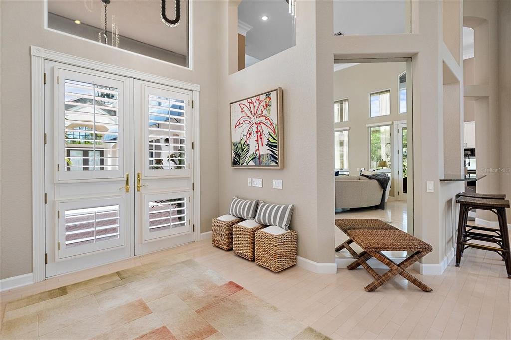 An entryway features double doors with shutters, a woven bench, and a patterned area rug — 617 WESTON POINTE COURT, LONGBOAT KEY, FL