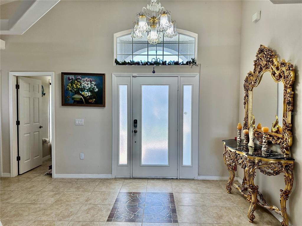 An entryway features a tiled floor with an inlay, a chandelier, and an ornate gold console — 1947 FAIRWAY LOOP, KISSIMMEE, FL
