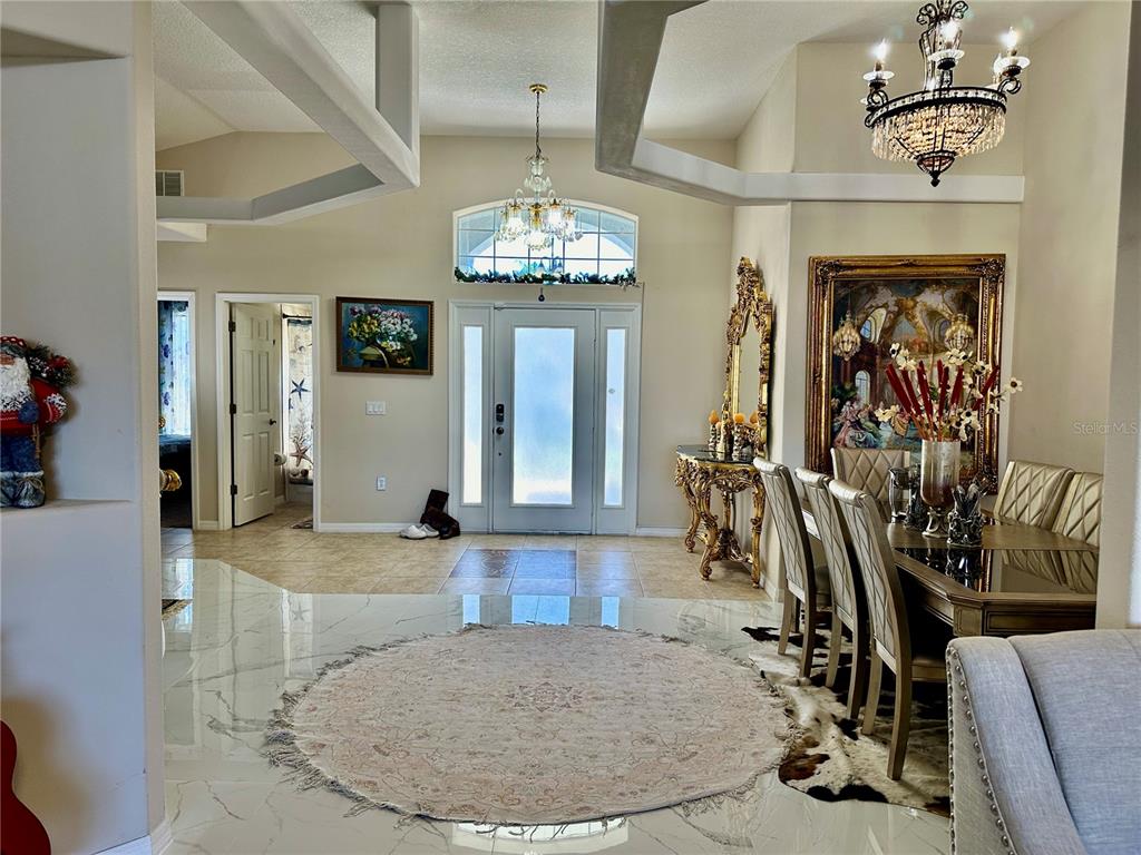 A foyer with a circular rug, tile flooring, and a dining area with a chandelier — 1947 FAIRWAY LOOP, KISSIMMEE, FL