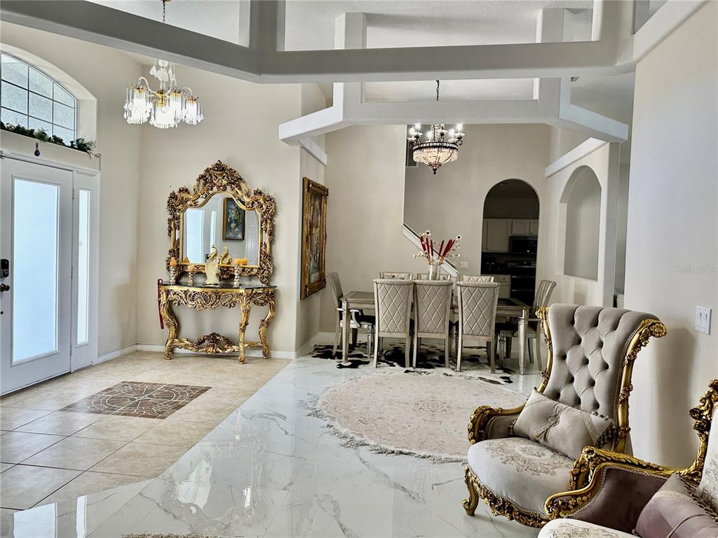 A formal dining area and entryway feature marble floors, ornate gold furniture, and crystal chandeliers — 1947 FAIRWAY LOOP, KISSIMMEE, FL