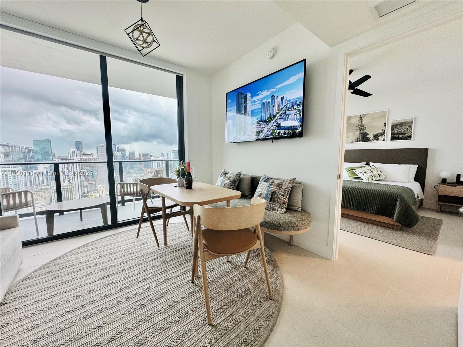 A dining area with a round rug and balcony view sits beside a bedroom doorway — 159 NE 6th St # 4314, Miami FL 33132, MIAMI, FL