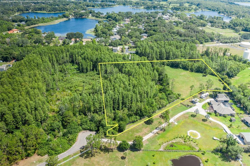 An aerial view shows a large, wooded plot of land outlined in yellow near houses — 0 TRACKSIDE DRIVE, ODESSA, FL