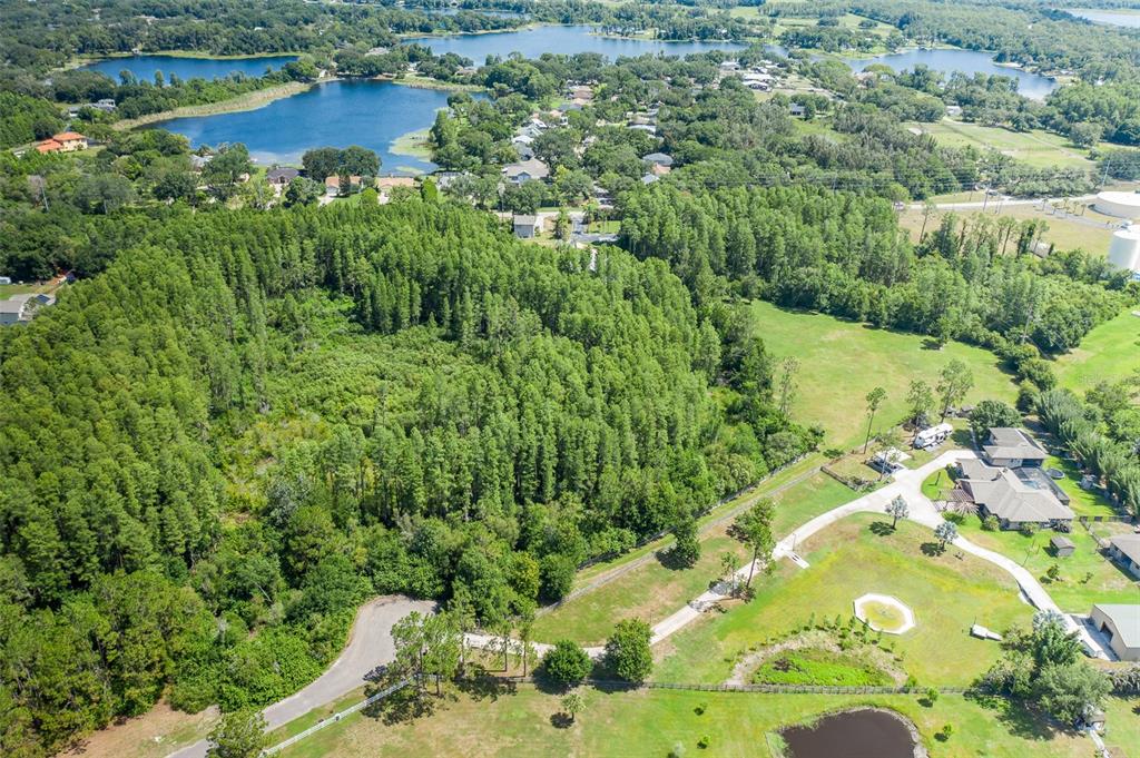 An aerial view shows a large wooded area adjacent to a residential property and lakes — 0 TRACKSIDE DRIVE, ODESSA, FL
