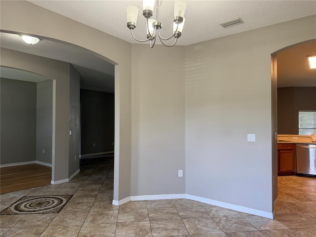 A dining area with tile flooring, a chandelier, and arched entryways leading to other rooms — 29 FORSYTHE LANE, PALM COAST, FL