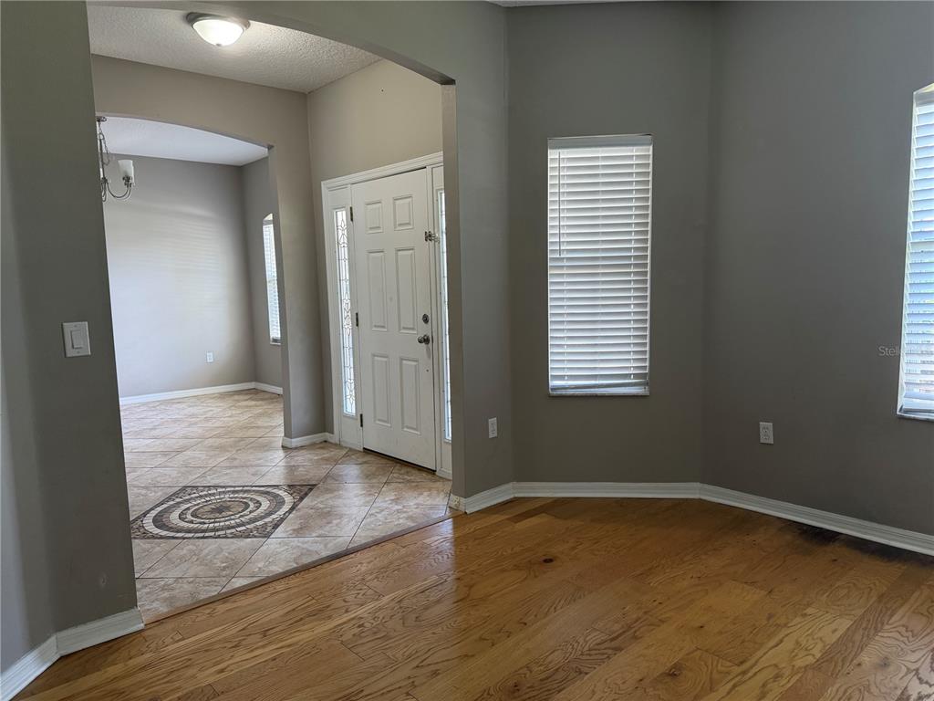 An entryway with tiled flooring leads to a living area featuring hardwood floors and windows — 29 FORSYTHE LANE, PALM COAST, FL