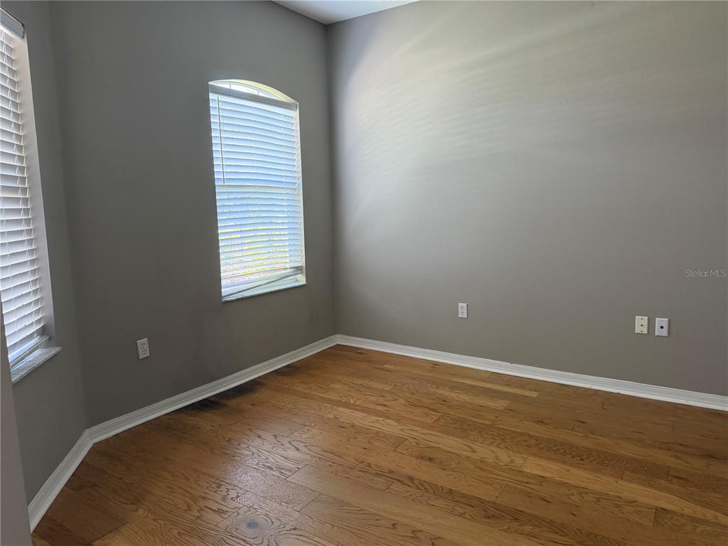 An empty room features gray walls, hardwood flooring, and two windows with white blinds — 29 FORSYTHE LANE, PALM COAST, FL