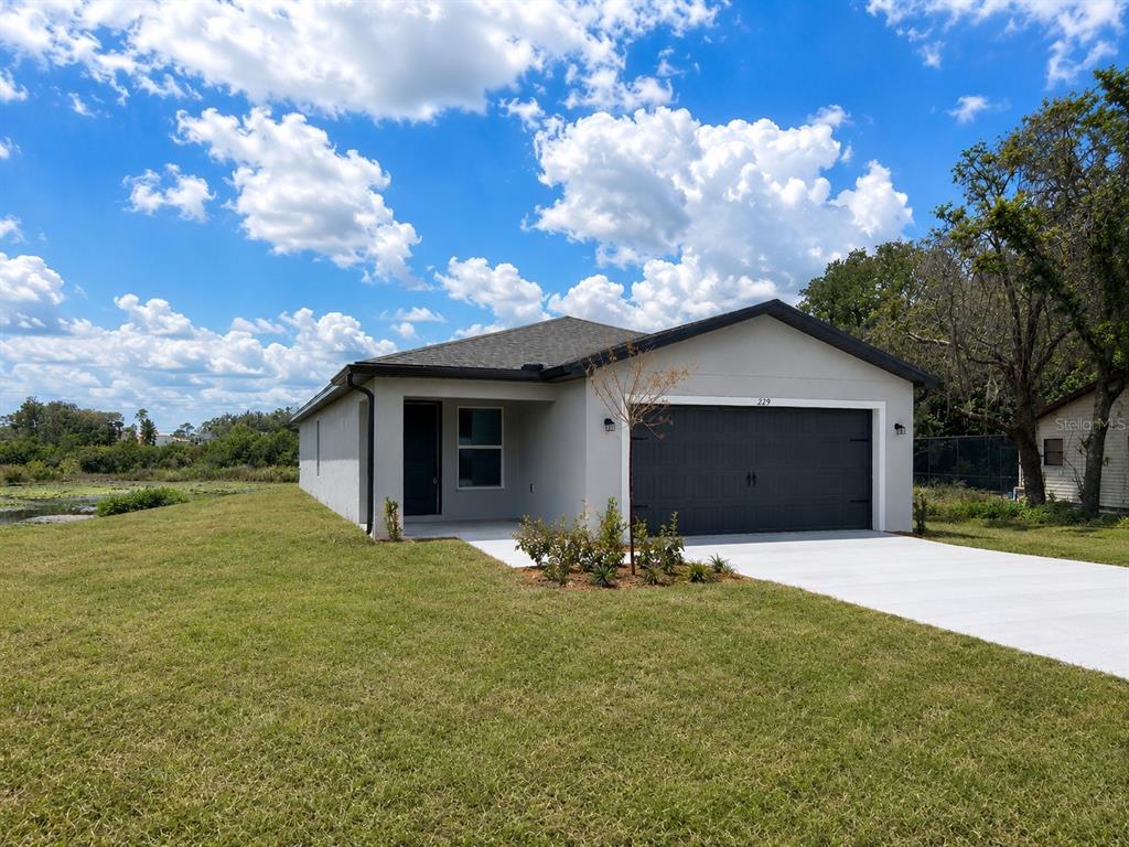 A single-story house with a gray exterior, dark garage door, and a concrete driveway — 229 GALAXY AVENUE, SPRING HILL, FL