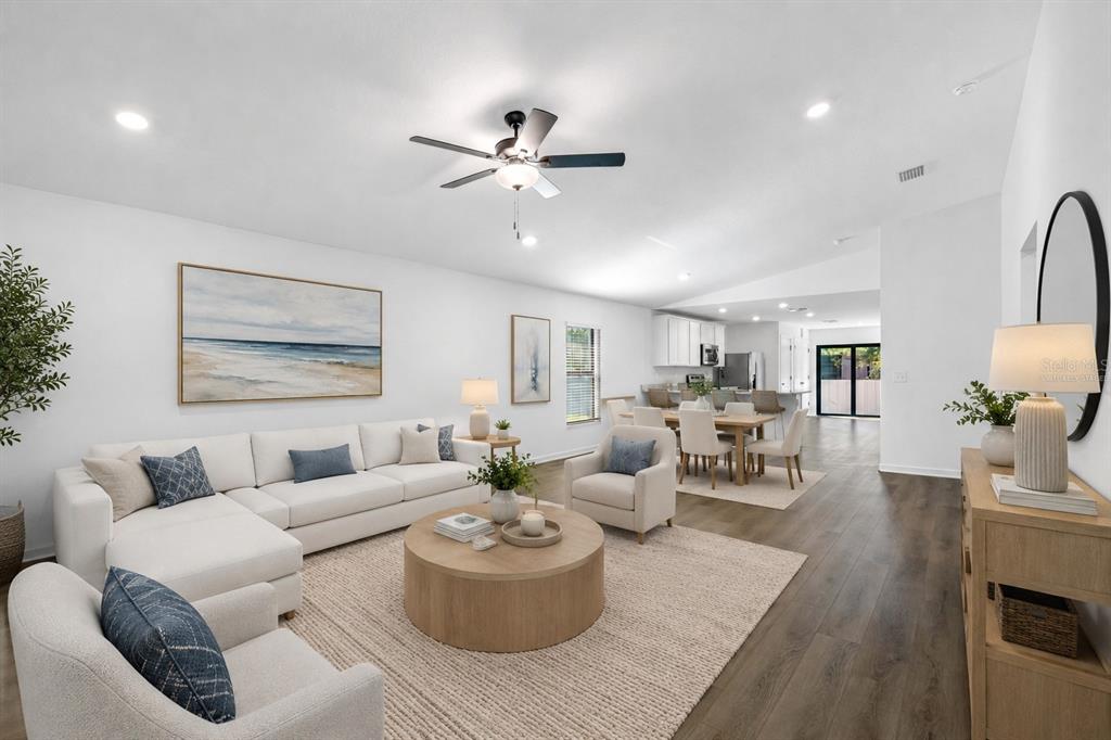 An open-concept living and dining area features white walls, wood flooring, and neutral furniture — 229 GALAXY AVENUE, SPRING HILL, FL