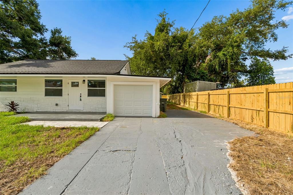 A single-story white house with a garage and a wooden fence along the driveway — 1509 15TH AVE W, BRADENTON, FL