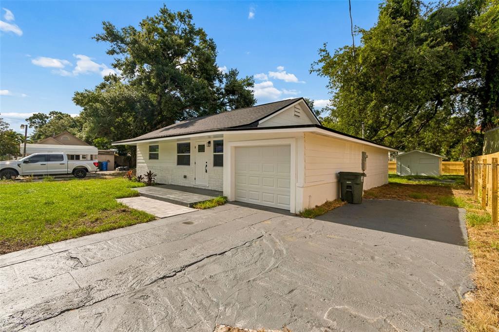 A white single-story house with a garage, a paved driveway, and a small front patio — 1509 15TH AVE W, BRADENTON, FL