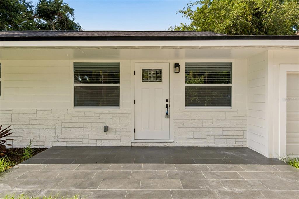A white house exterior features a front door, two windows, and a tiled porch — 1509 15TH AVE W, BRADENTON, FL