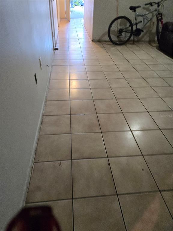 A hallway with beige square floor tiles leads toward an open doorway — 572 MAINELINE BOULEVARD, APOPKA, FL