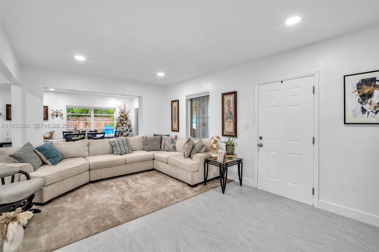 A living room features a large beige sectional sofa, a rug, and a white door — 14140 NE 10th Ave, North Miami FL 33161, NORTH MIAMI, FL