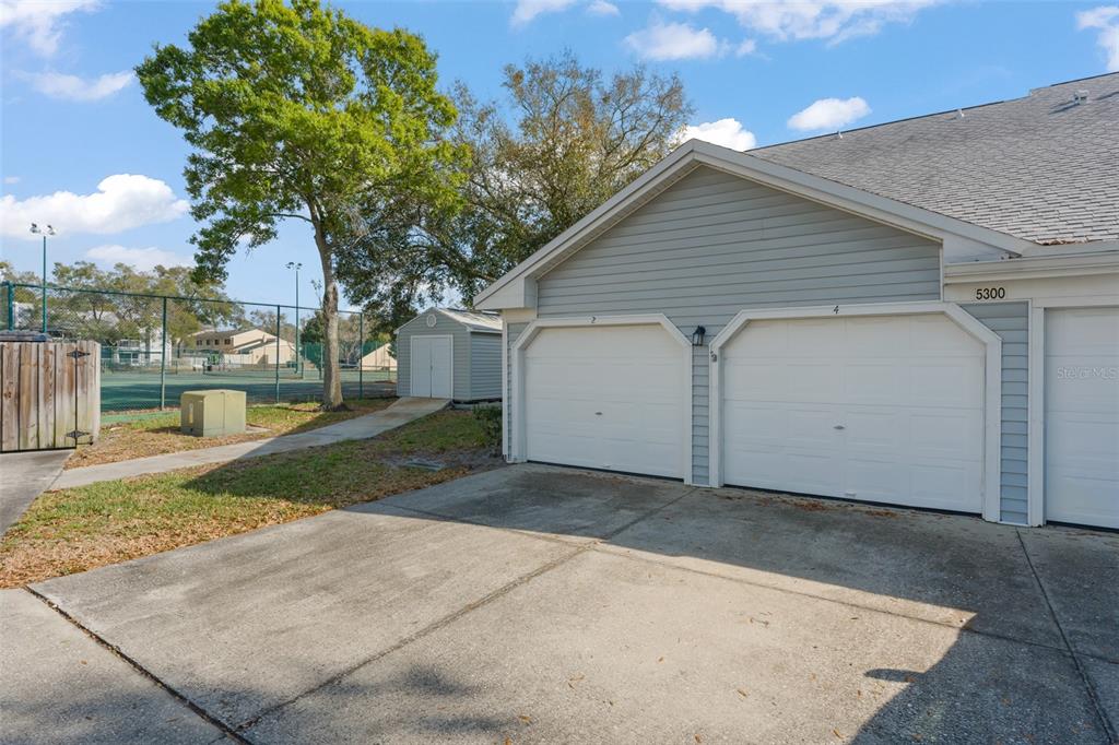 A view of a residential building with two garage doors and a small storage shed — 5300 DOVER VILLAGE LANE UNIT 4, ORLANDO, FL