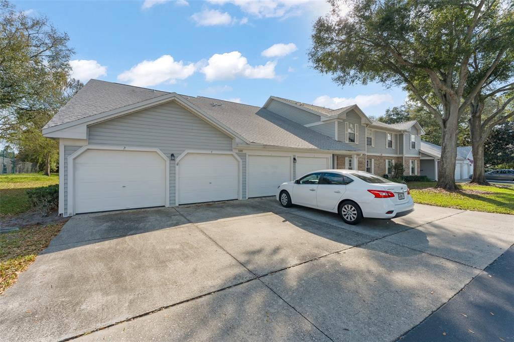 A white sedan is parked in front of a multi-unit building with three garage doors — 5300 DOVER VILLAGE LANE UNIT 4, ORLANDO, FL