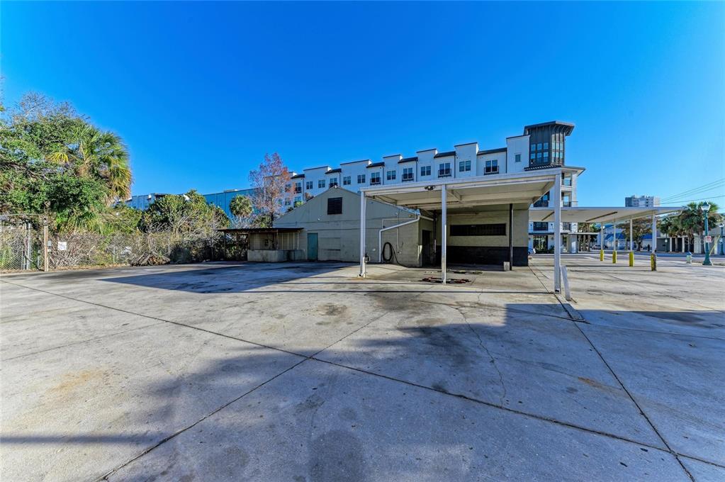 A paved parking lot sits in front of a small building with a covered bay — 400 W CENTRAL AVENUE, SARASOTA, FL