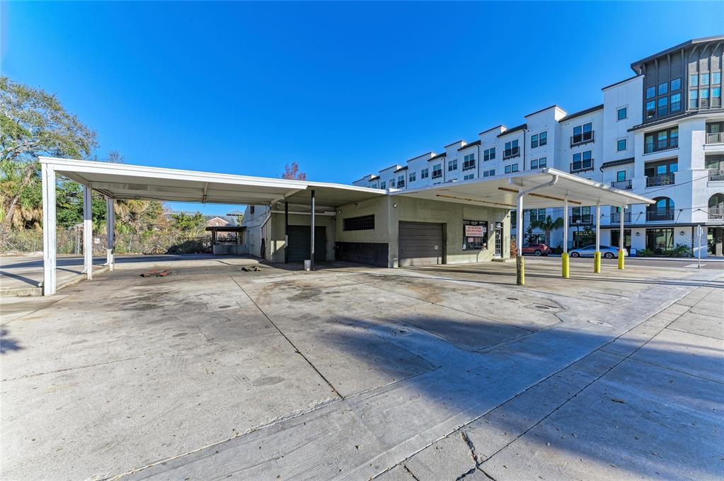 An exterior view of a commercial building with a large concrete lot and metal canopy — 400 W CENTRAL AVENUE, SARASOTA, FL