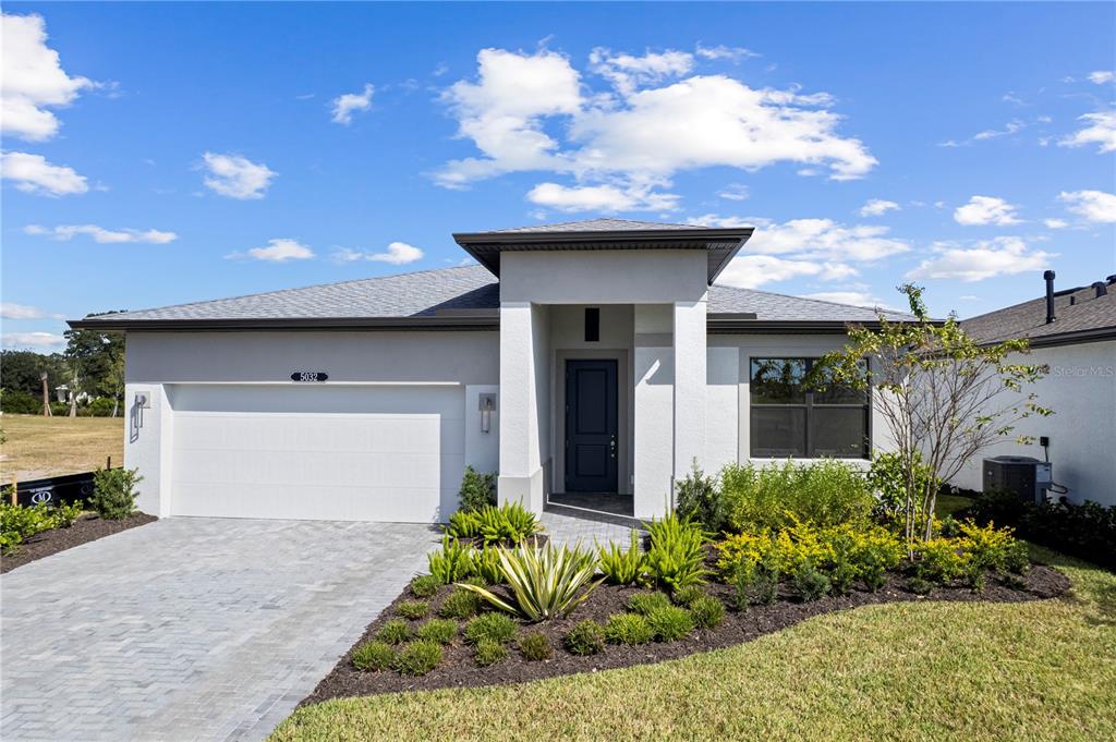 A single-story house with a white stucco exterior, a gray roof, and a paved driveway — 5032 LOWLAND TERRACE, PARRISH, FL