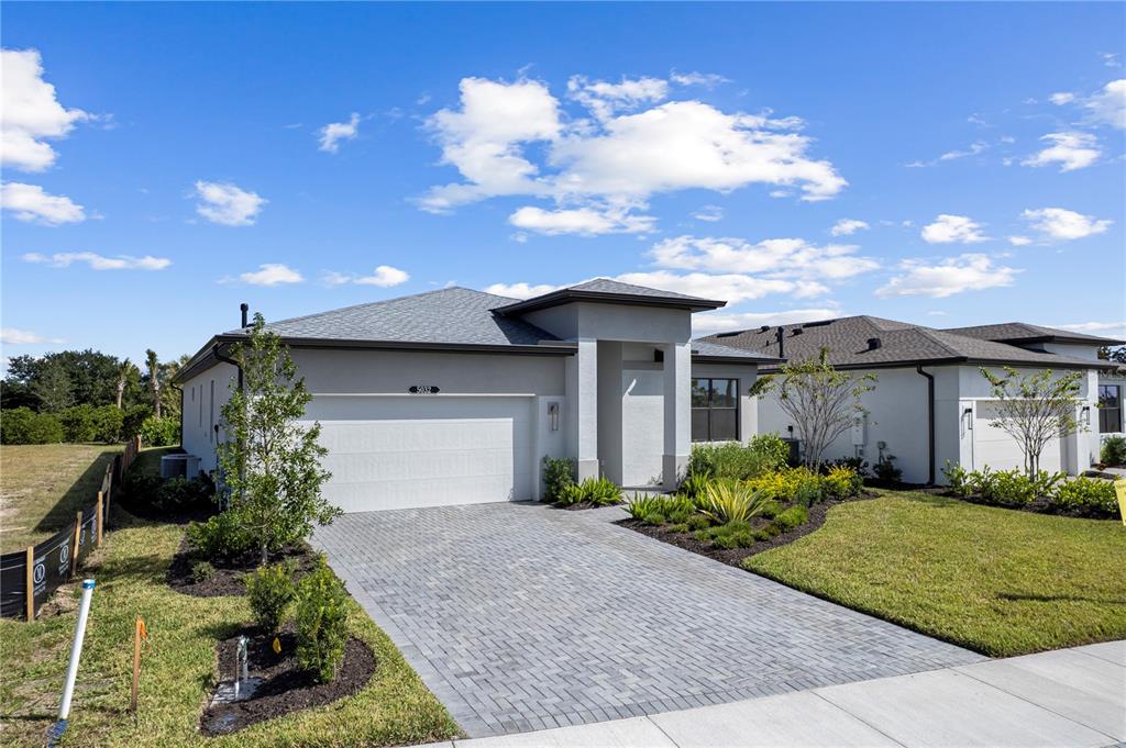 A modern single-story house with a gray stucco exterior and a paved driveway — 5032 LOWLAND TERRACE, PARRISH, FL