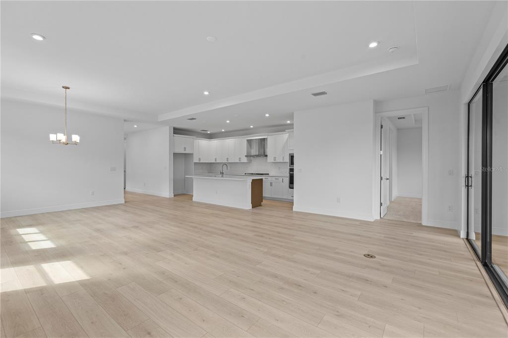 An open-concept kitchen and living area feature light wood flooring, white cabinetry, and recessed lighting — 5032 LOWLAND TERRACE, PARRISH, FL