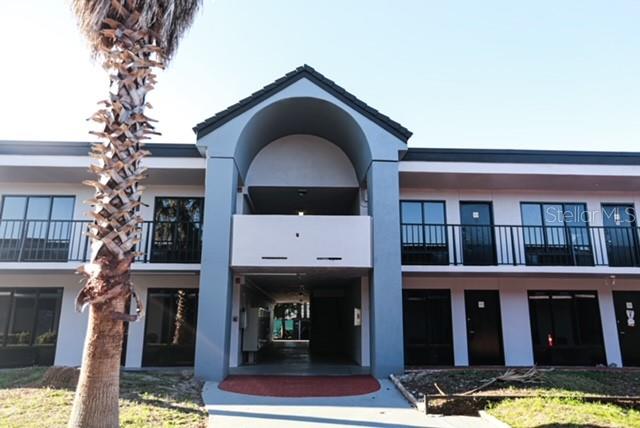 A two-story apartment building features a central arched entryway and a palm tree in front — 8421 S ORANGE BLOSSOM TRAIL UNIT 436, ORLANDO, FL