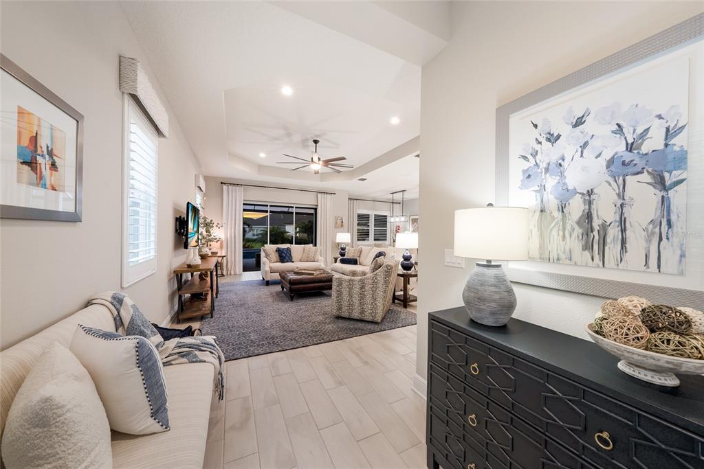 A view from a foyer looking into a living room with tile floors and furniture — 12825 COASTAL BREEZE WAY, BRADENTON, FL