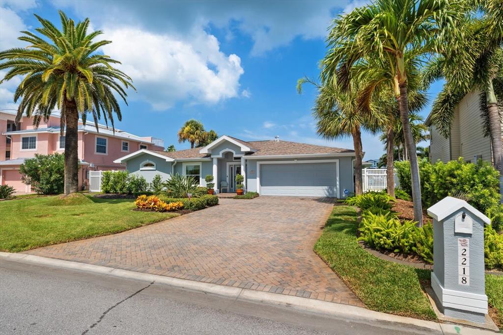 A single-story house with a paved driveway, palm trees, and a gray exterior — 2218 DONATO DRIVE, BELLEAIR BEACH, FL