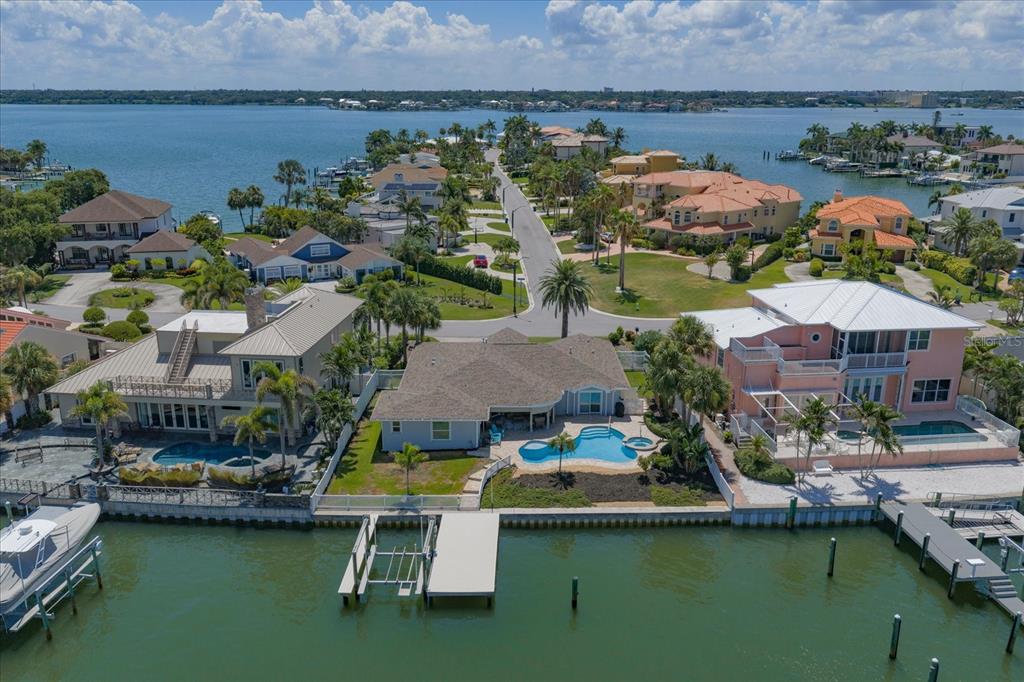 An aerial view of waterfront houses with private docks, swimming pools, and a paved street — 2218 DONATO DRIVE, BELLEAIR BEACH, FL