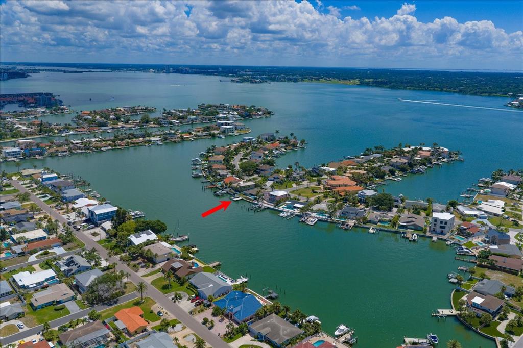 An aerial view shows a waterfront house with a boat dock on a canal — 2218 DONATO DRIVE, BELLEAIR BEACH, FL