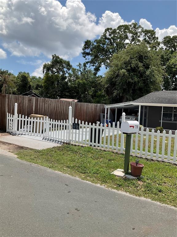A white picket fence encloses a concrete driveway next to a house with a carport — 710 E JACKSON STREET, KISSIMMEE, FL