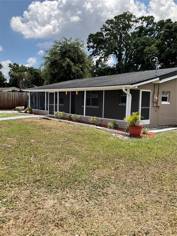 A single-story house with a dark gray exterior and a screened-in porch sits on grass — 710 E JACKSON STREET, KISSIMMEE, FL
