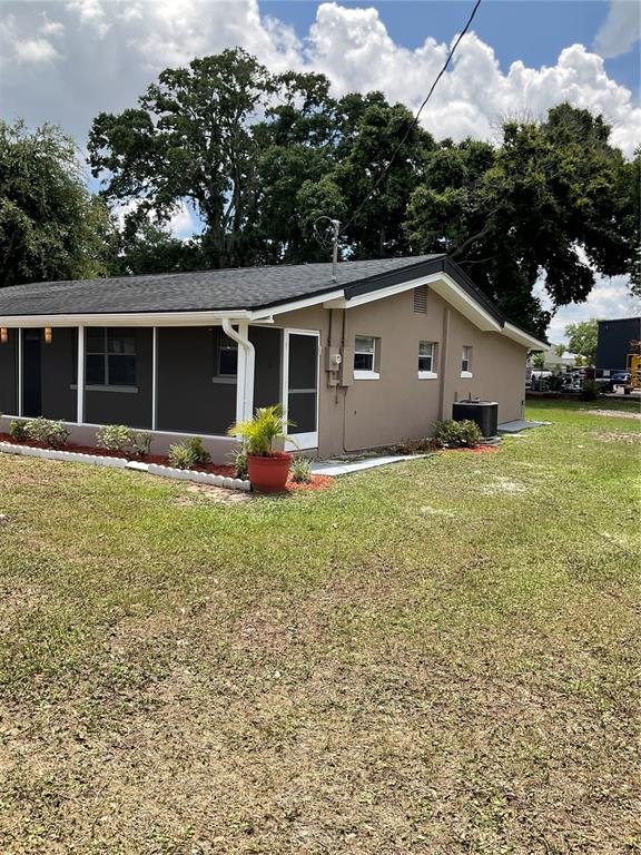 The exterior of a single-story house features tan siding, a dark roof, and a screened porch — 710 E JACKSON STREET, KISSIMMEE, FL