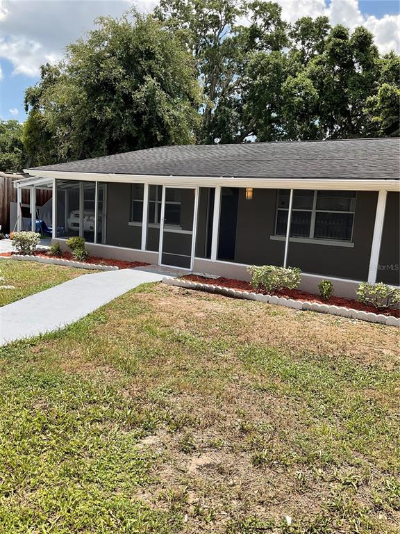 A single-story house with a screened-in porch and a concrete walkway sits on a lawn — 710 E JACKSON STREET, KISSIMMEE, FL
