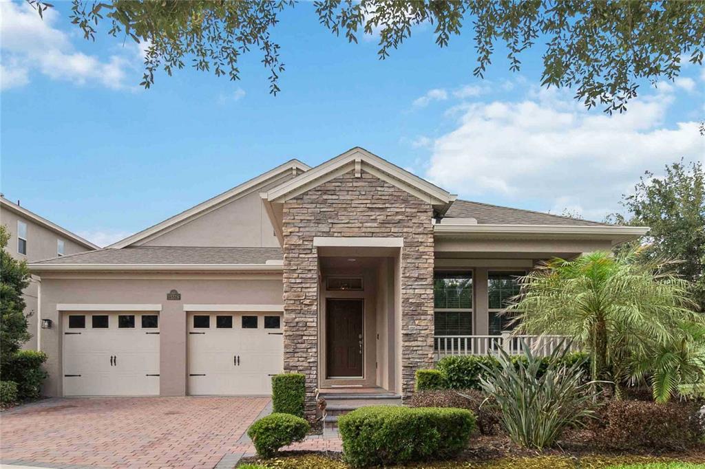 A single-story house with a stone facade, two-car garage, and a paved driveway — 15518 FOUNTAIN COVE COURT, WINTER GARDEN, FL