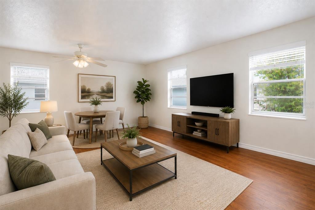 A living room with wood flooring, a beige sofa, a coffee table, and a television — 6940 SUNSET DRIVE S UNIT 2C, ST PETERSBURG, FL