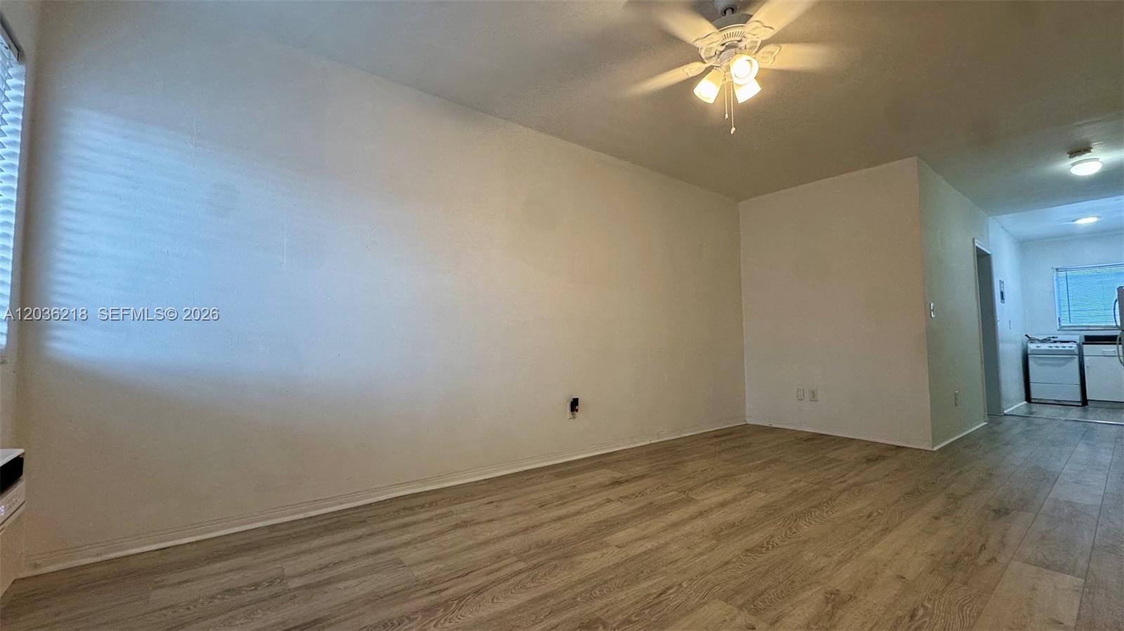 A living room with light wood-look flooring, white walls, and a ceiling fan — 7717 Byron Ave # 12, Miami Beach FL 33141, MIAMI BEACH, FL