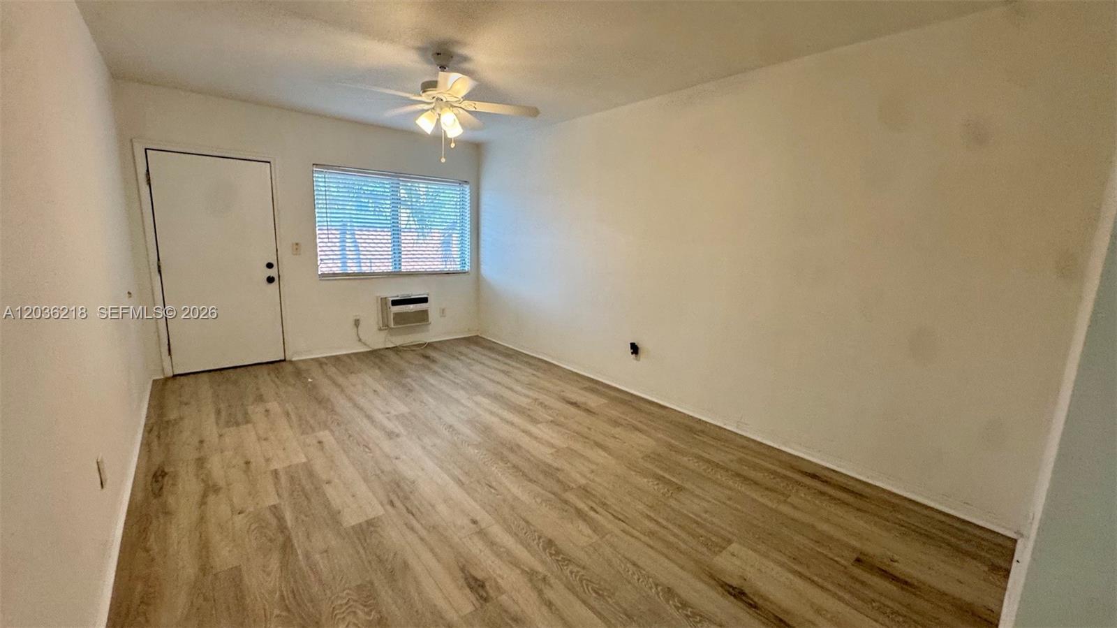 An empty room features light wood-look flooring, a ceiling fan, and a window air conditioner — 7717 Byron Ave # 12, Miami Beach FL 33141, MIAMI BEACH, FL